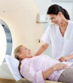 A medical professional helps a patient into an MRI machine