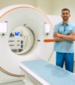 A MRI technologist posing in front of an MRI machine