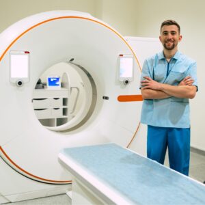 A MRI technologist posing in front of an MRI machine