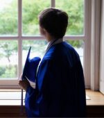 A new graduate looking out a window