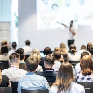 A group of people listen to a speaker making a presentation