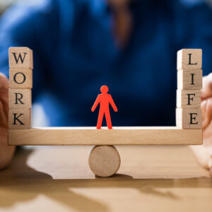 A paper cutout of a person balancing between work and life