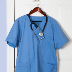 Scrubs hanging up on a clothes hanger placed on a door