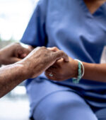 A nurse holding a patient's hand