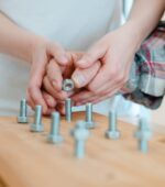 An occupational therapist helps an man screw bolts