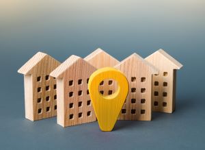 wooden blocks shaped like houses with a yellow destination pin in front-center